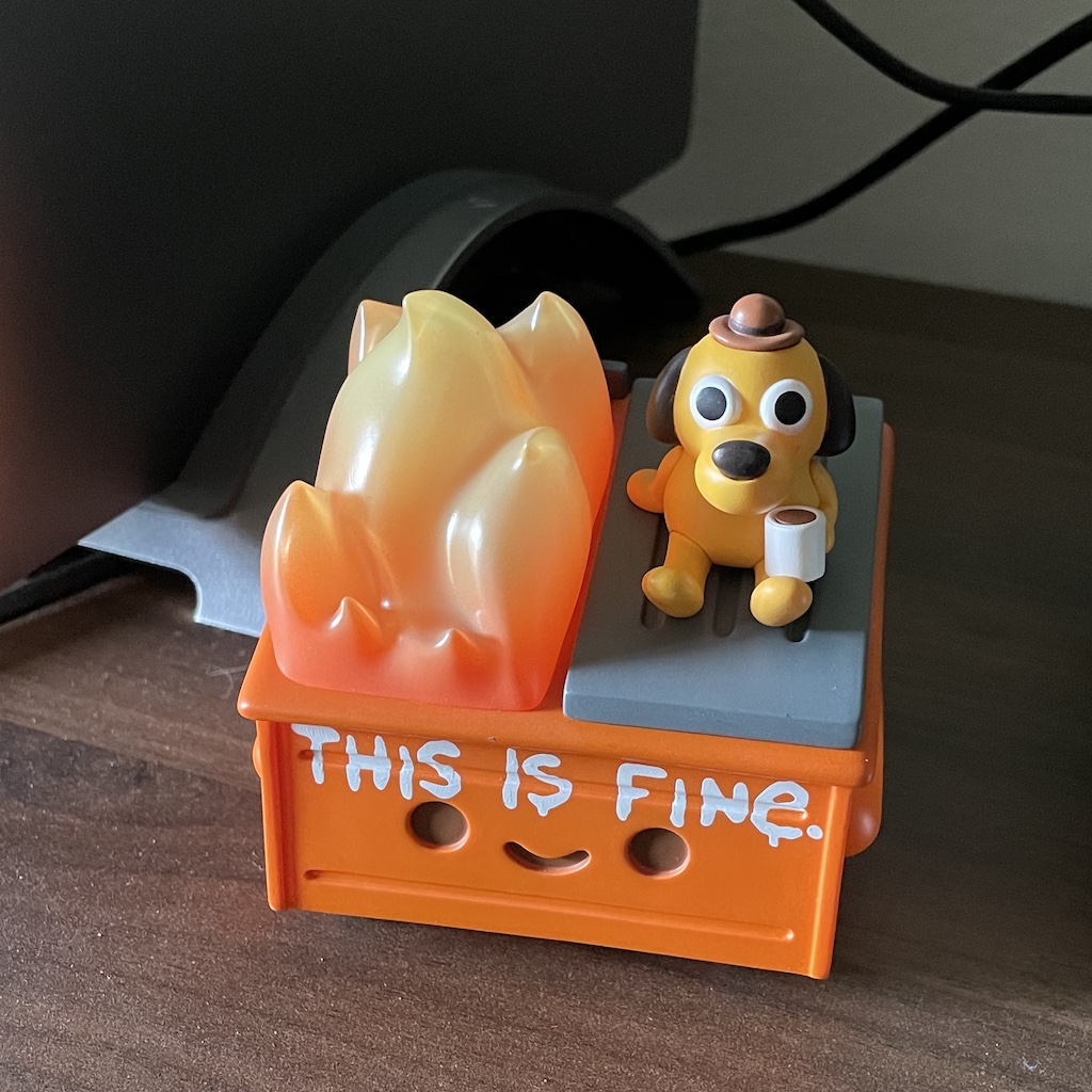 figurine of combination of dumpster fire and &quot;this is fine&quot; memes