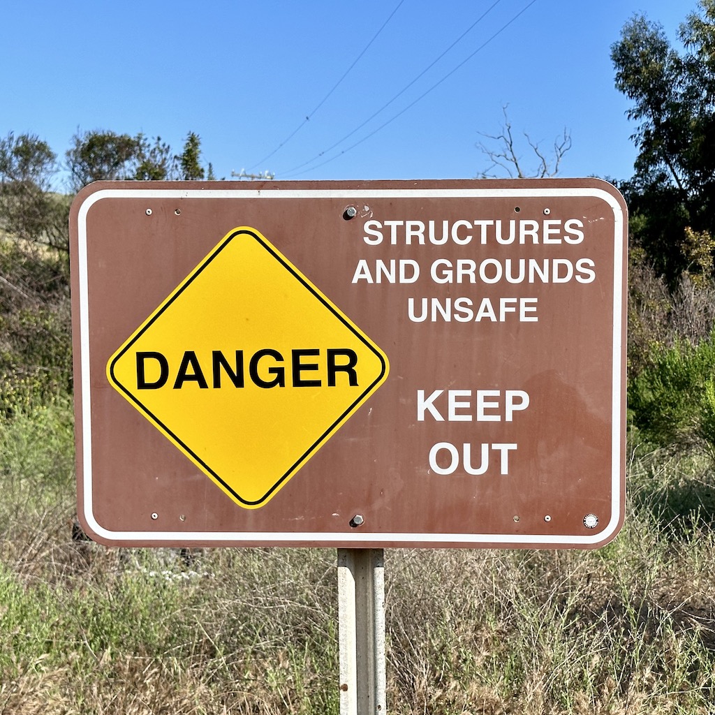 sign saying “Danger: Structures and Grounds Unsafe, Keep Out”