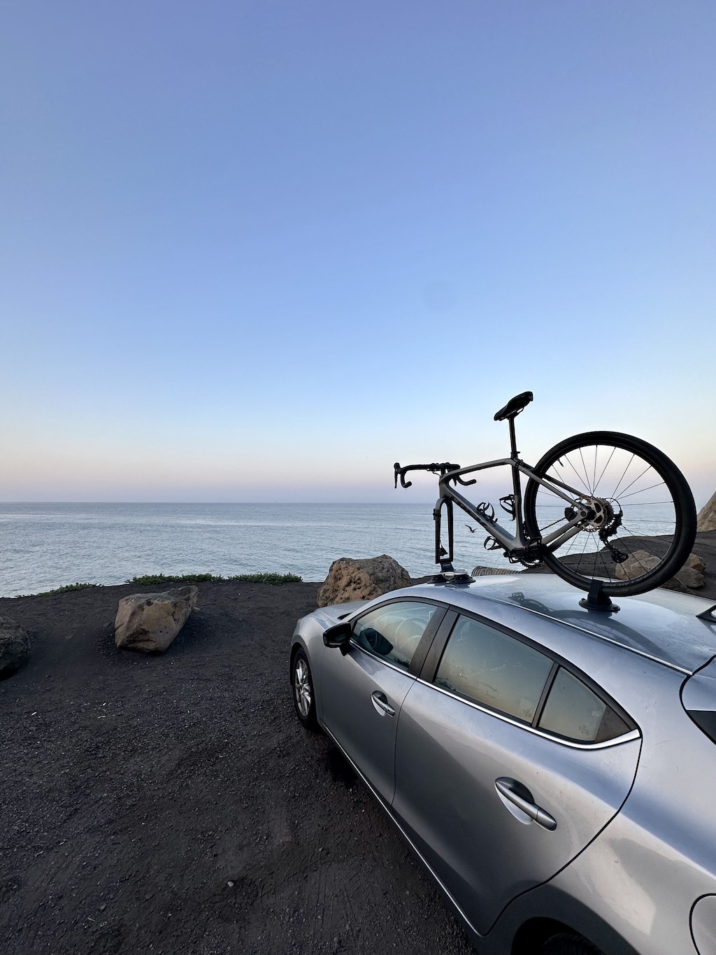 bicycle mounted on the roof of a car parked by the Pacific Ocean